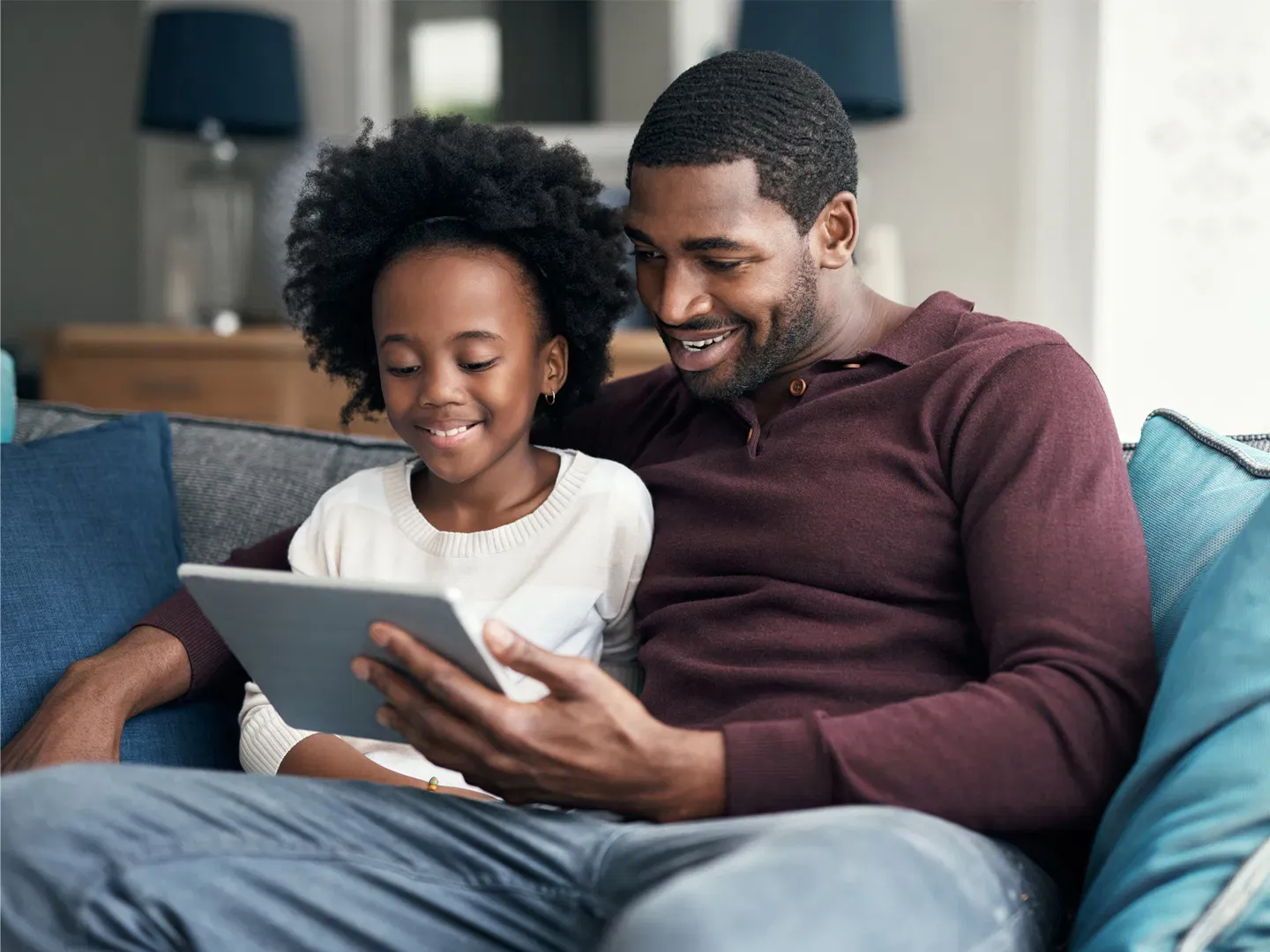 A smiling Father and Daughter laughing at some great internet content together.